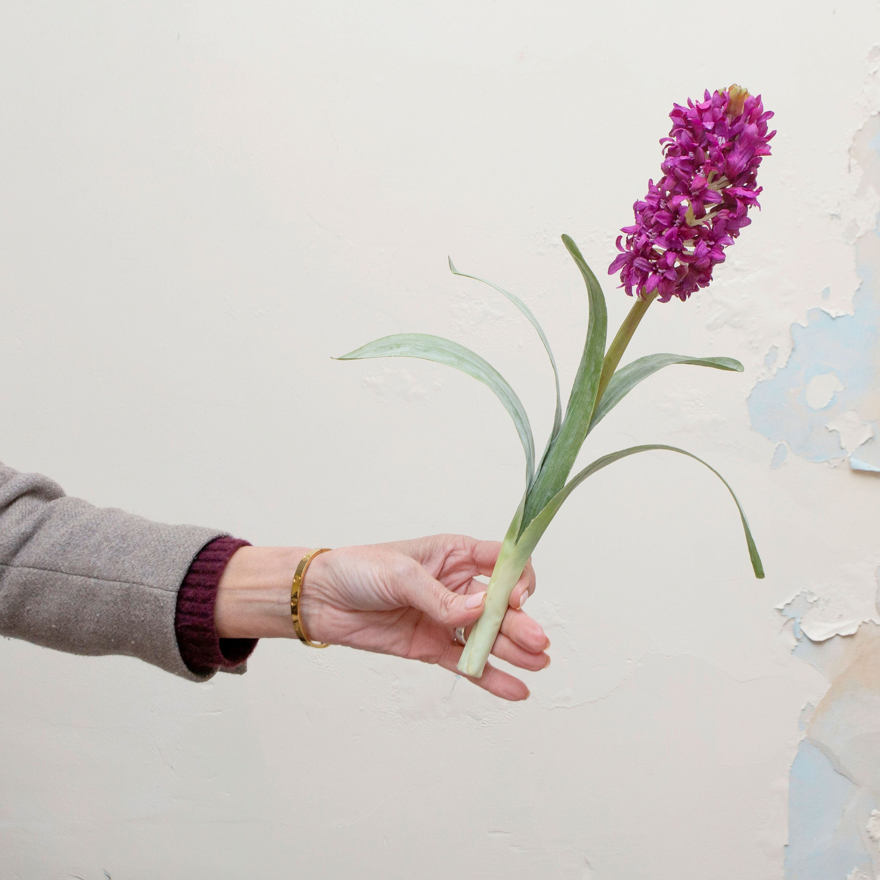 Artificial purple hyacinth stem held in hand, featuring a dense flower spike and long green leaves