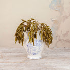 Artificial green birch foliage spray stem displayed in a blue and white floral ceramic vase