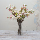 Artificial light pink blossom spray stems displayed together in a vase for styling purposes.