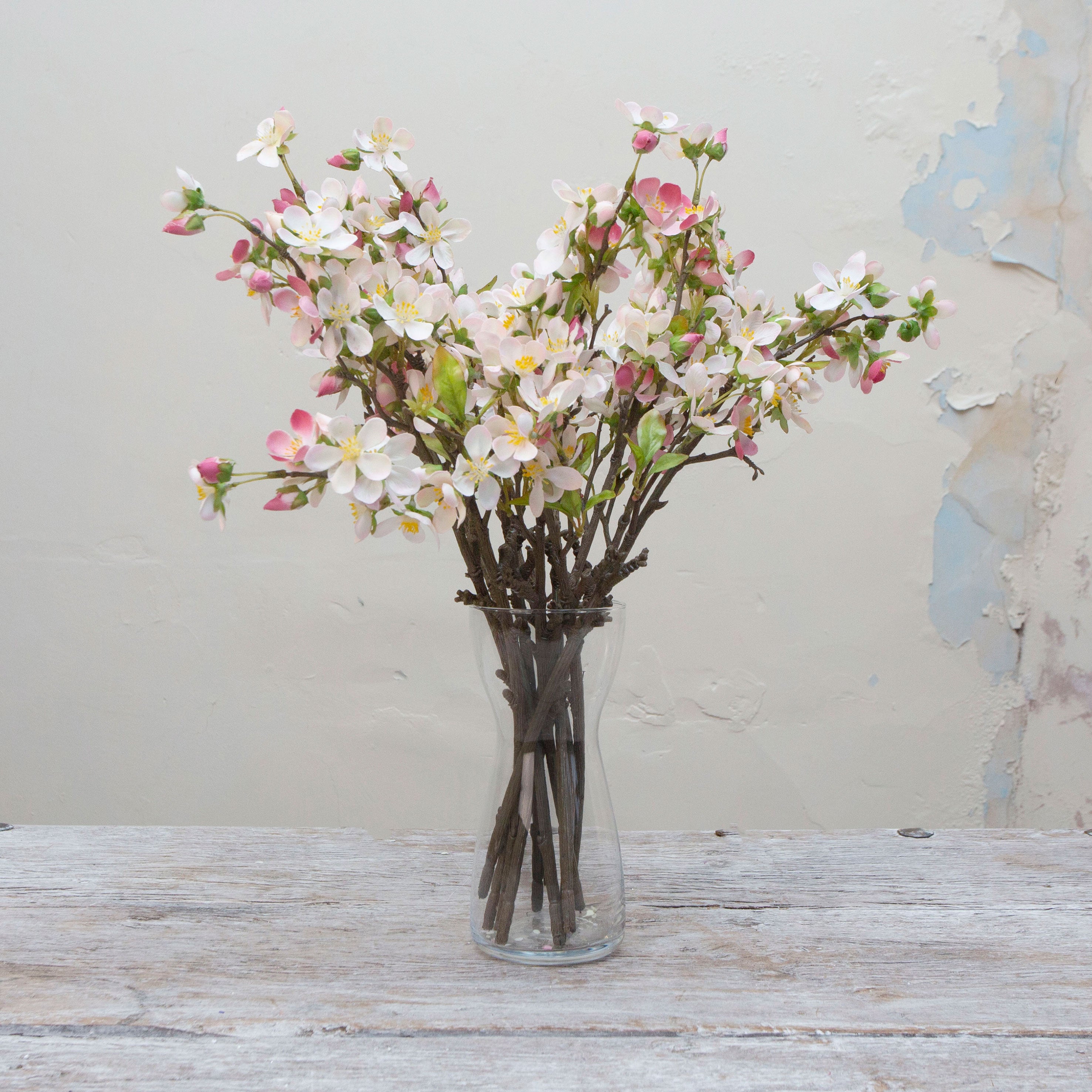 Artificial light pink blossom spray stems displayed together in a vase for styling purposes.