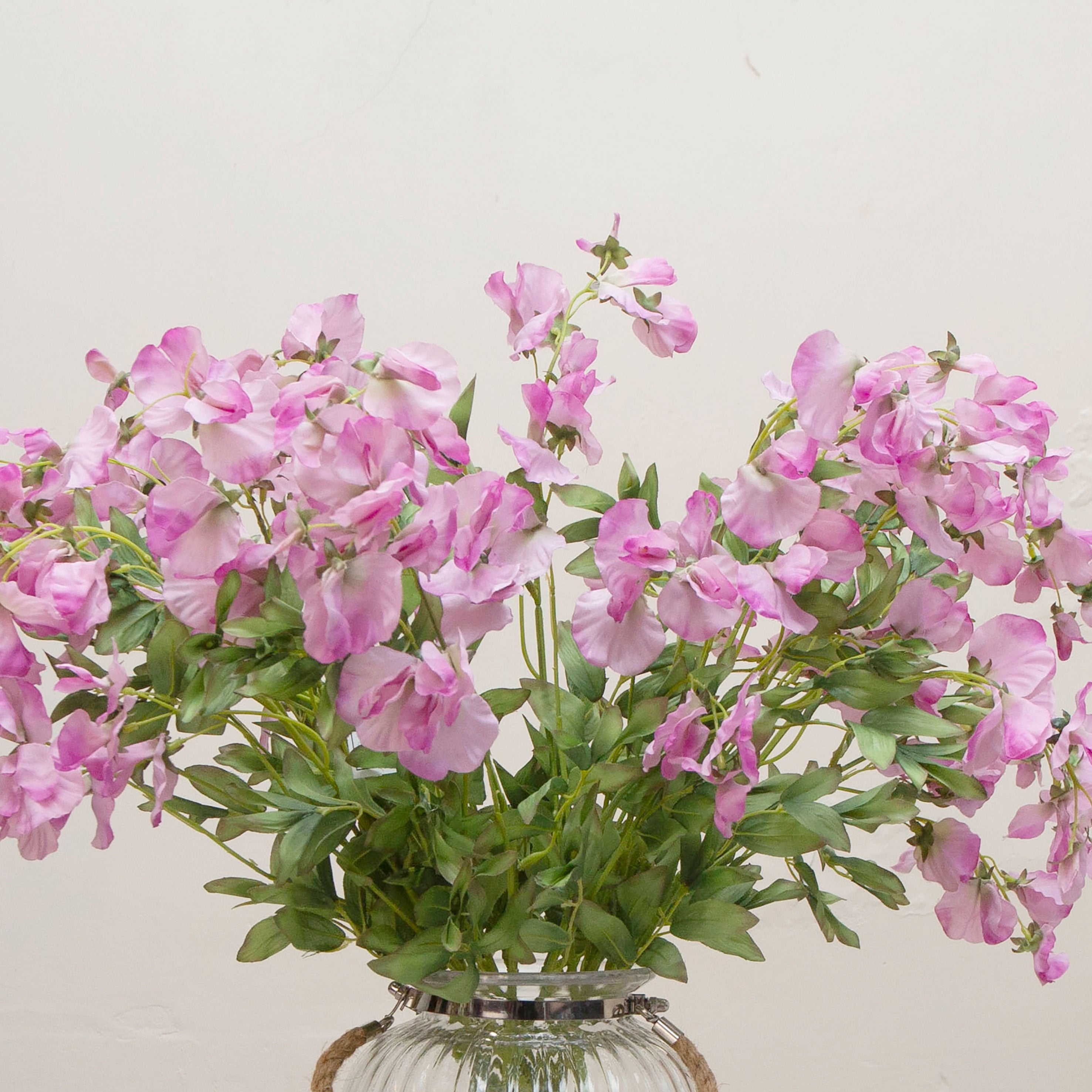 Close-up of artificial sweet pea flowers, showing soft purple-pink petals, gentle colour gradation and naturally shaped, flexible stems