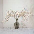 Artificial pale pink dancing orchid stems displayed together in a vase for styling purposes.