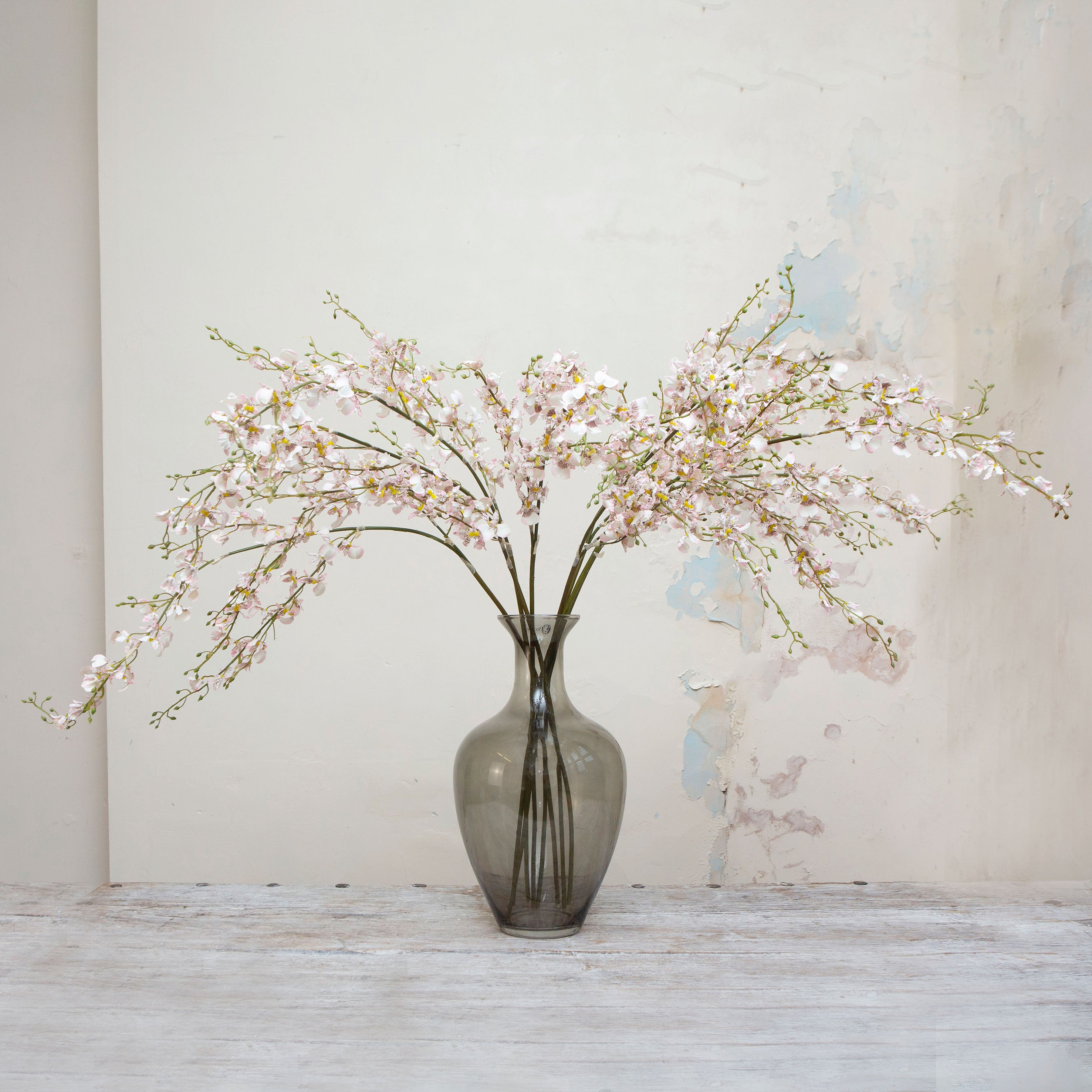 Artificial pale pink dancing orchid stems displayed together in a vase for styling purposes.