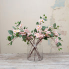 Artificial pale pink clematis stem displayed in a vase, showing delicate climbing-style stems, airy pink blooms and natural foliage for an elegant, romantic arrangement