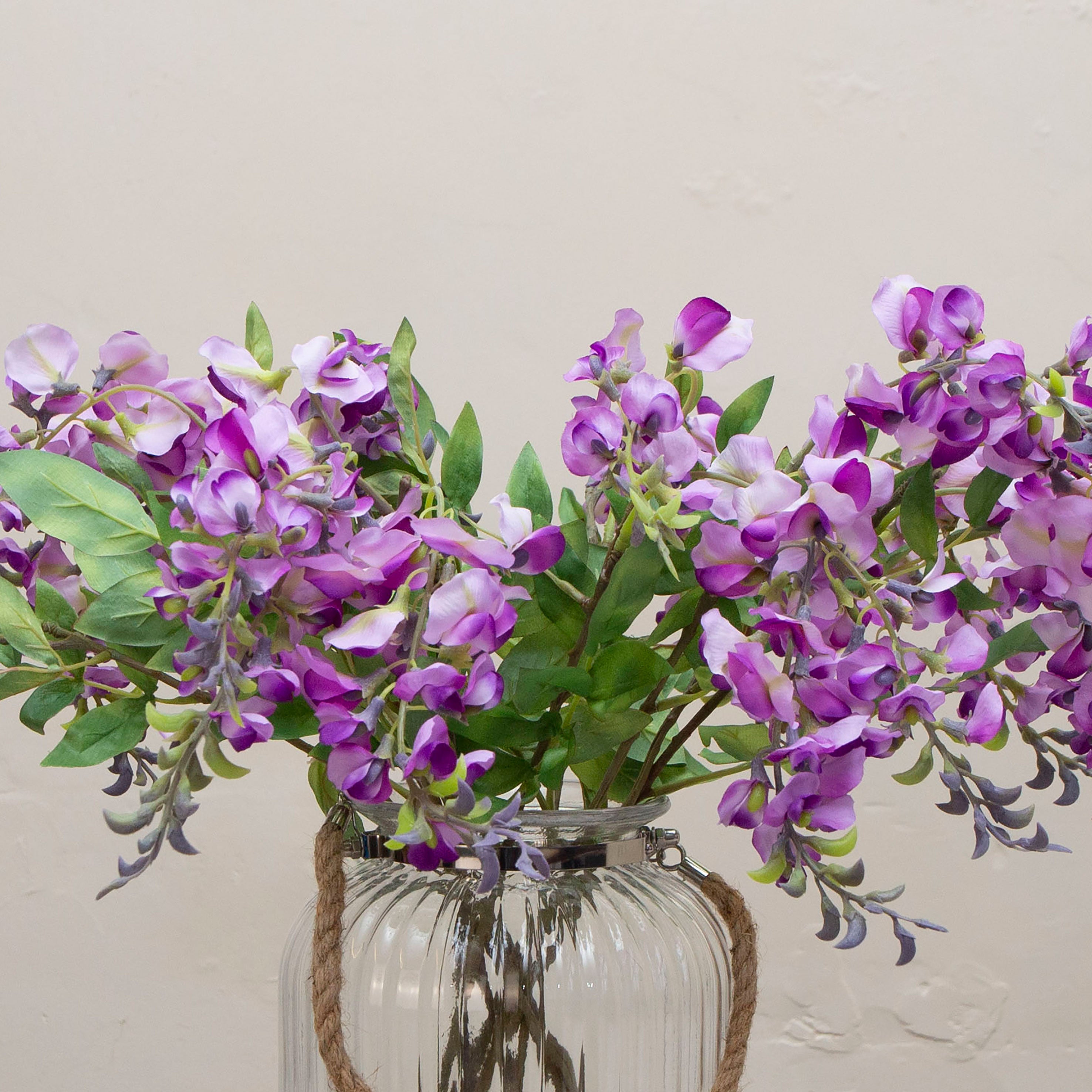 Close-up of artificial purple wisteria flowers, showing soft lavender-purple petals, subtle tonal variation and natural bud detailing