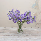 Artificial lavender-blue sweet pea stems displayed together in a vase for styling purposes.