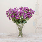 Artificial deep purple astrantia stem displayed in a vase, featuring airy branching stems, small star-like blooms and soft green foliage.