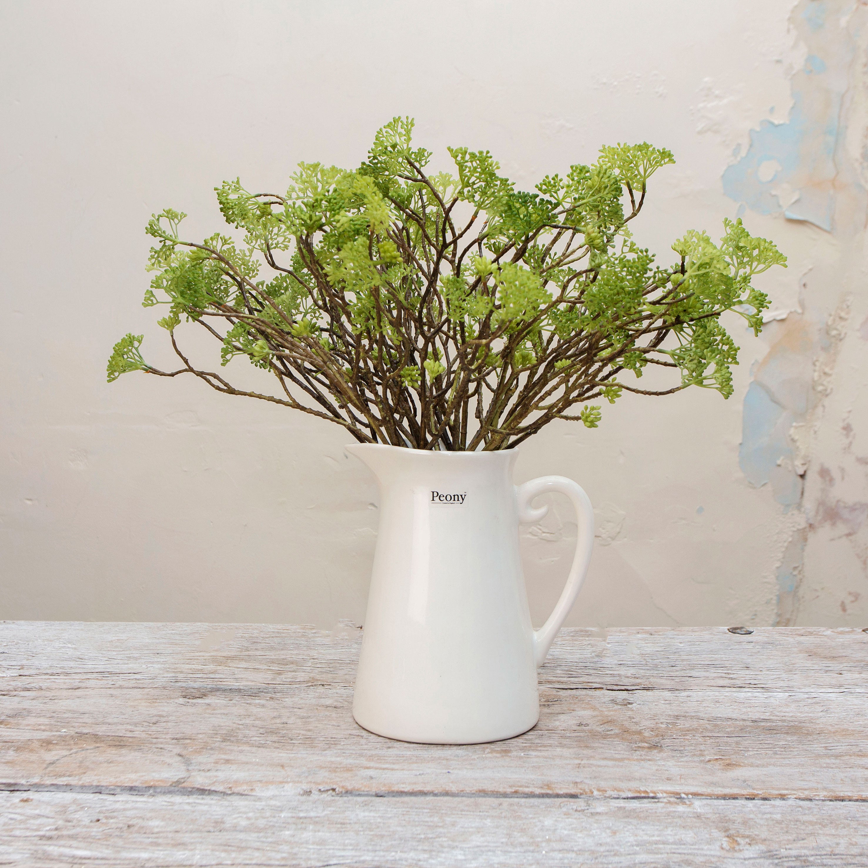 Artificial wild greenery foliage spray stems displayed together in a vase for styling purposes