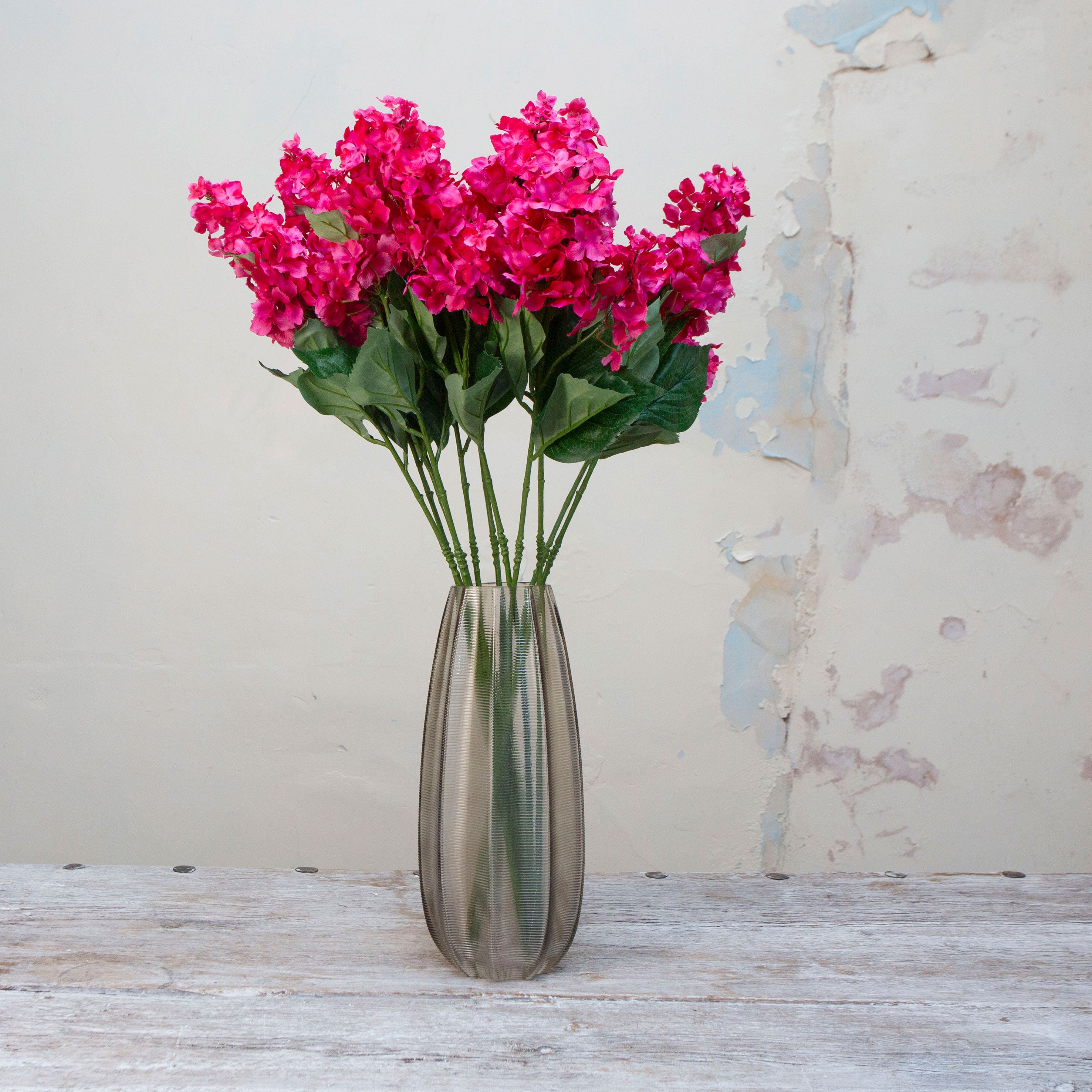 Artificial bright pink conehead hydrangea stems displayed together in a vase for styling purposes.