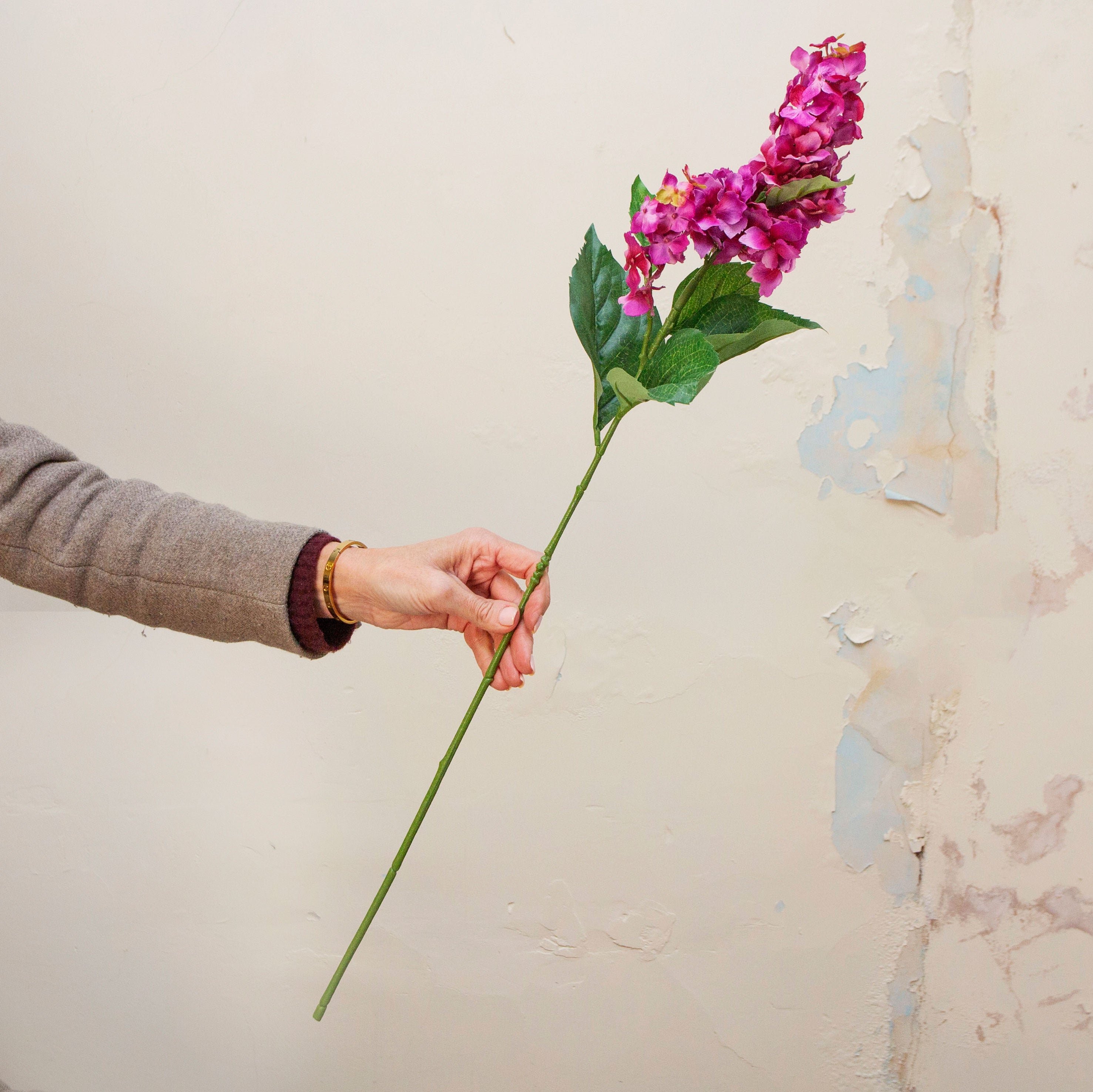 Artificial purple-pink conehead hydrangea  stem held in hand, featuring dense clustered blooms on an upright green stem
