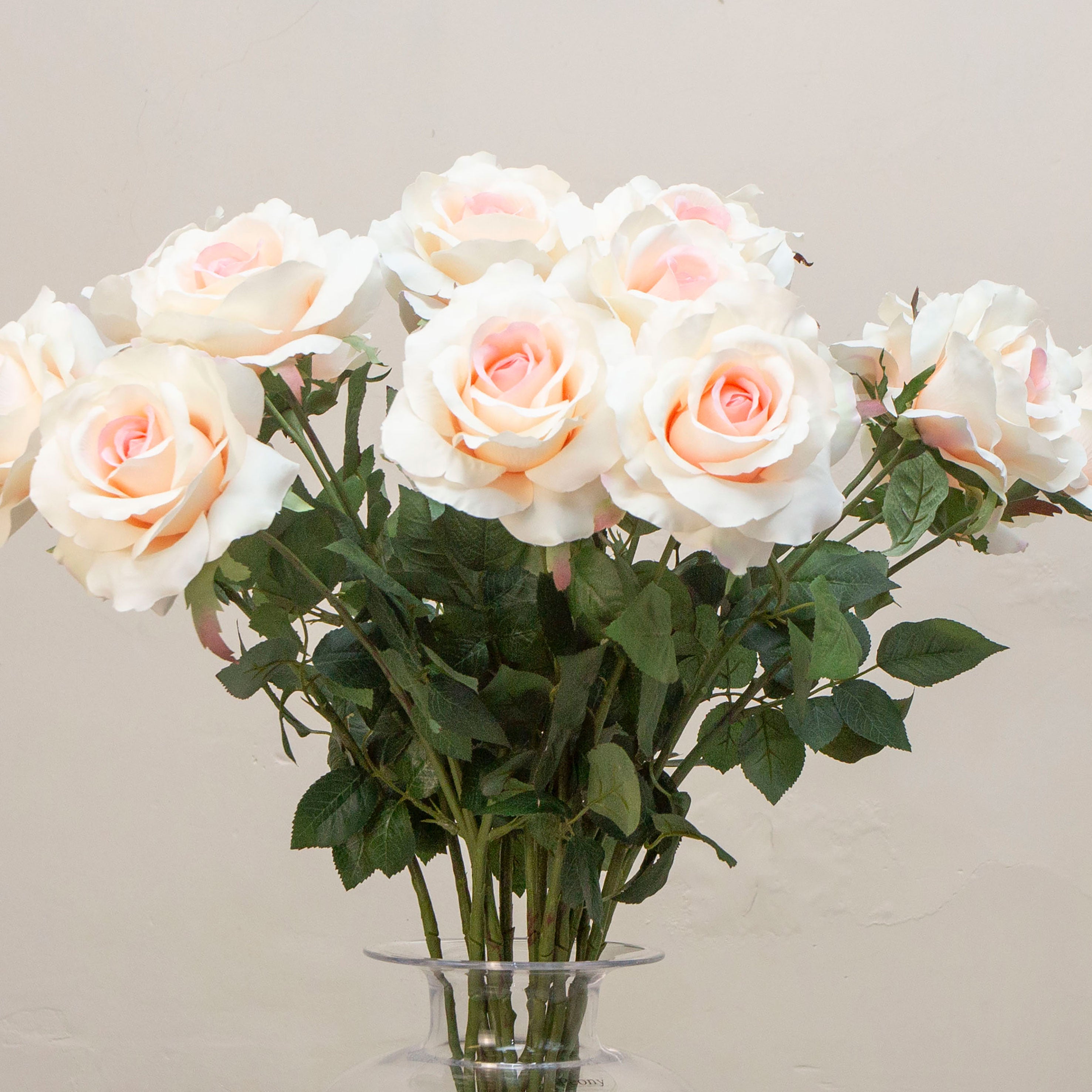 Close-up of artificial ivory rose flowers showing layered petals and subtle blush detail.