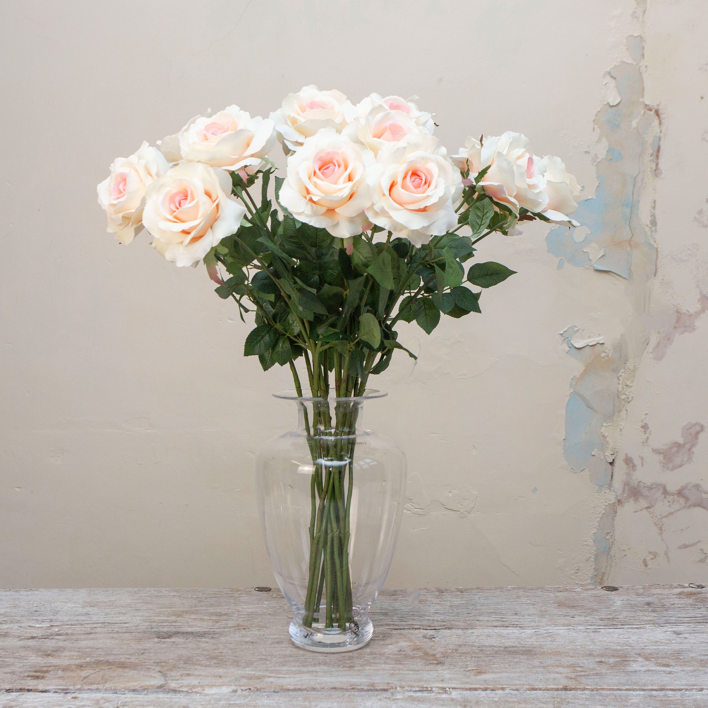 Artificial ivory rose stems with soft blush centres, displayed together in a clear glass vase for styling purposes.