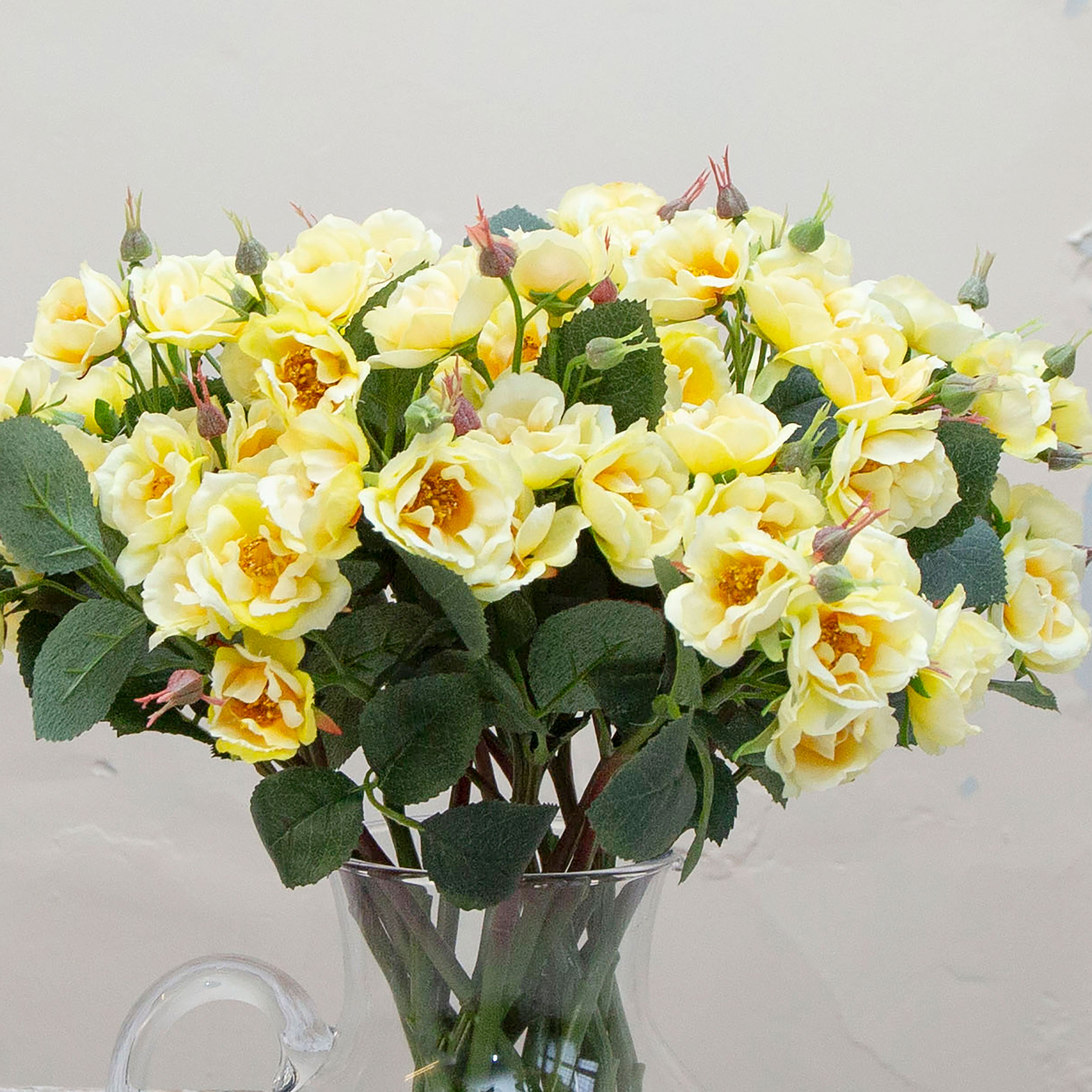 Close-up of artificial pale yellow rose flowers, highlighting gently cupped petals, soft buttery tones and realistic petal texture