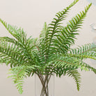 lose-up of artificial green fern spray foliage showing detailed fronds and texture.