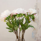 Close-up of artificial white peony flowers showing layered petals with soft blush detailing and natural texture