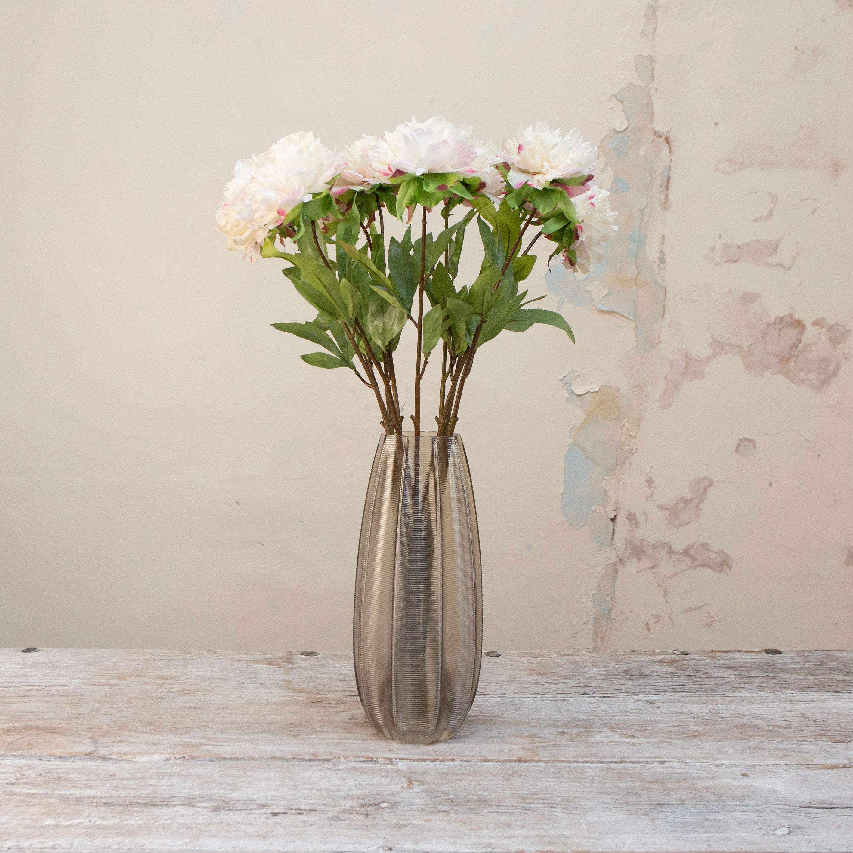 Artificial white peony stems displayed together in a vase for styling purposes