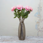 Artificial pale pink peony stems displayed together in a vase for styling purposes