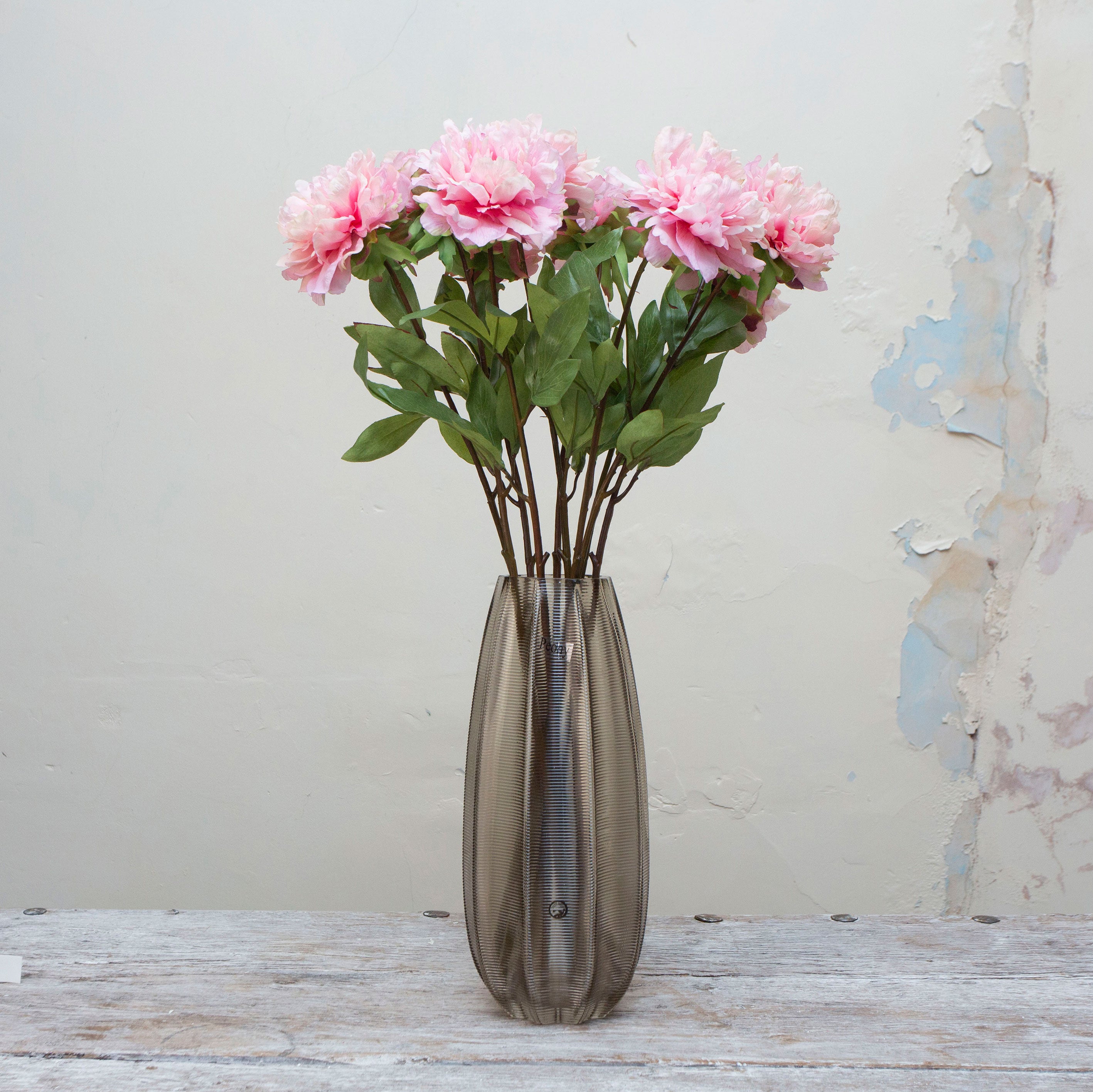 Artificial pale pink peony stems displayed together in a vase for styling purposes