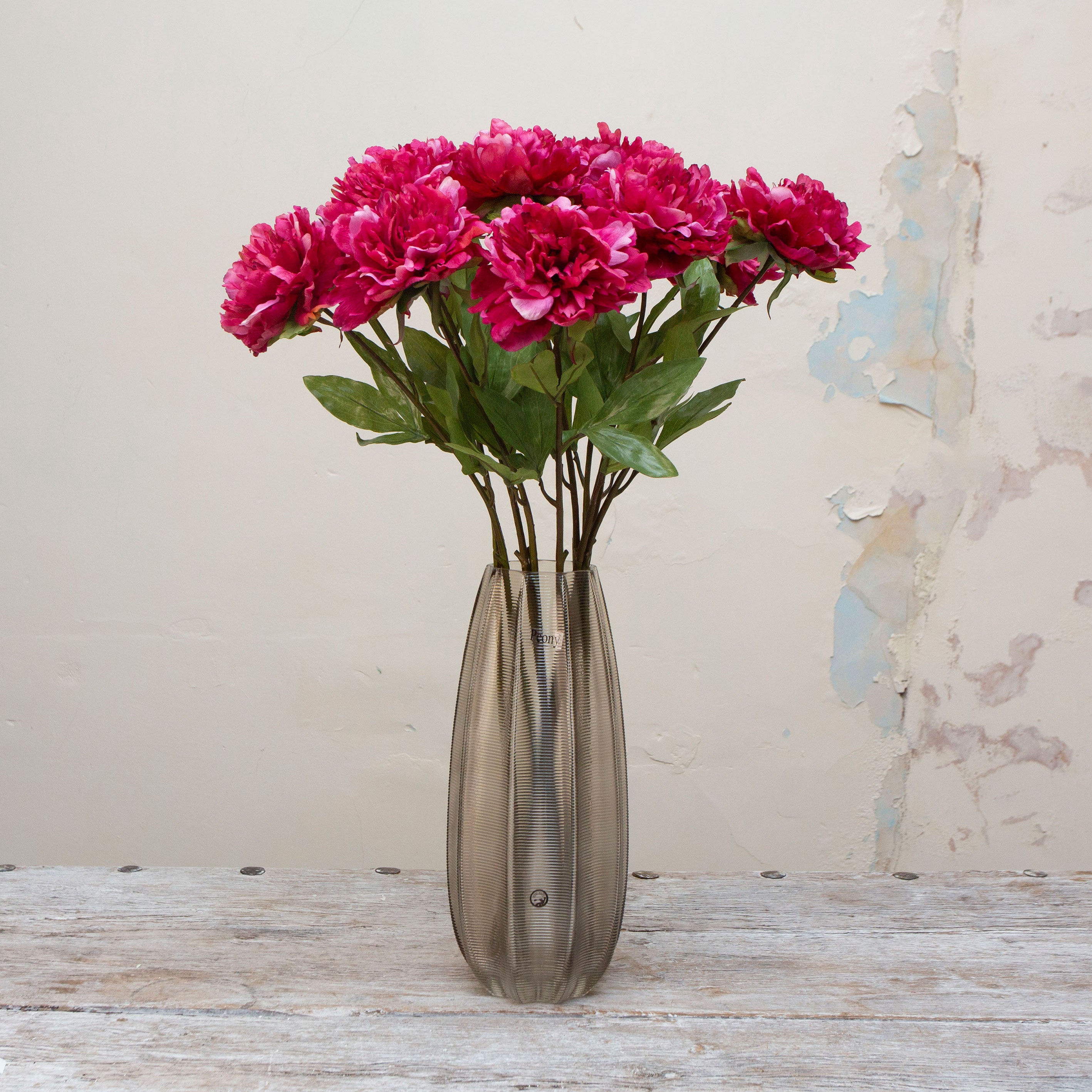 Artificial deep pink peony stems displayed together in a vase for styling purposes