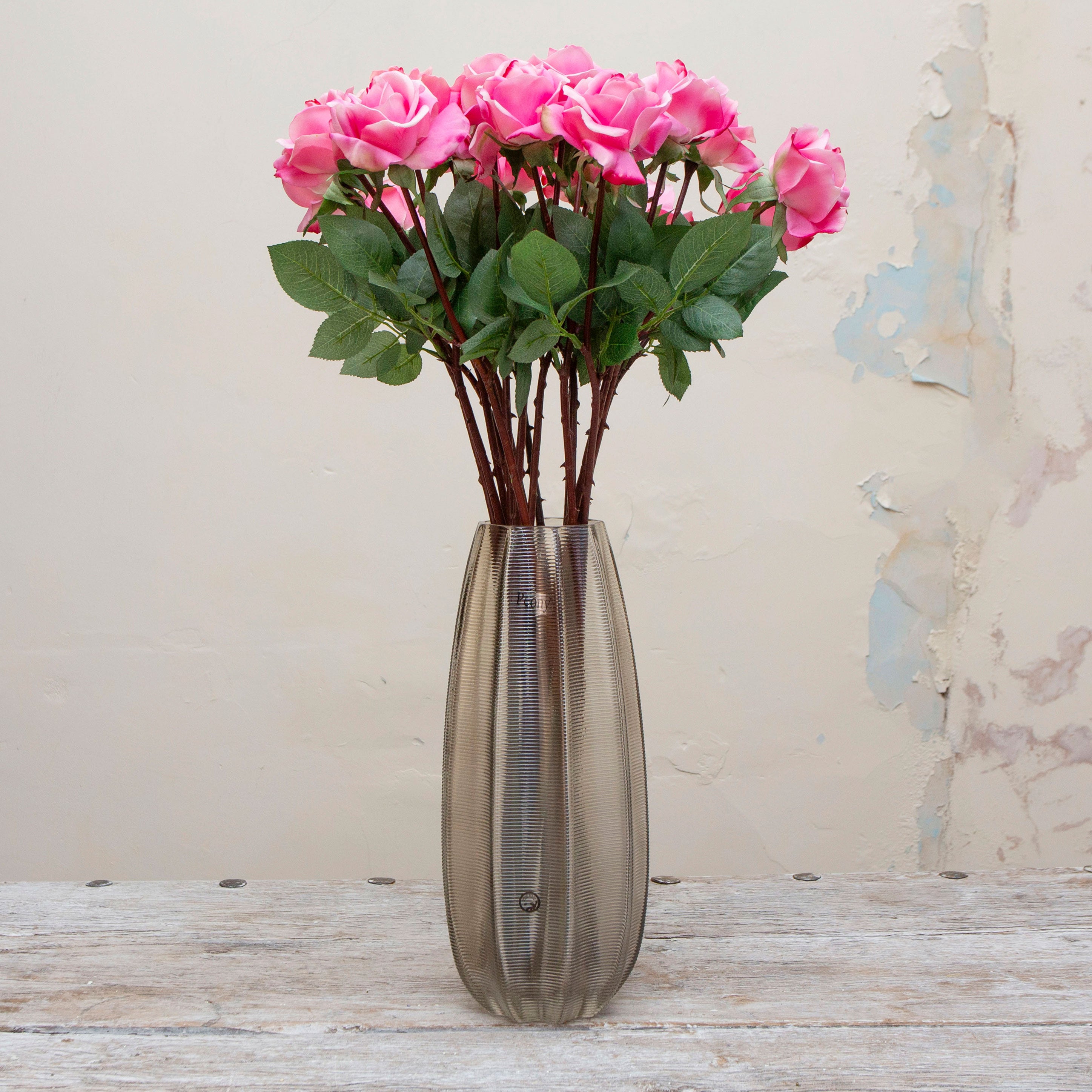 Artificial bright pink rose stem displayed in a vase, showcasing a fully formed rose bloom with rich pink colour and natural-looking leaves