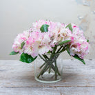 Artificial pink and white rhododendron stems displayed together in a vase for styling purposes
