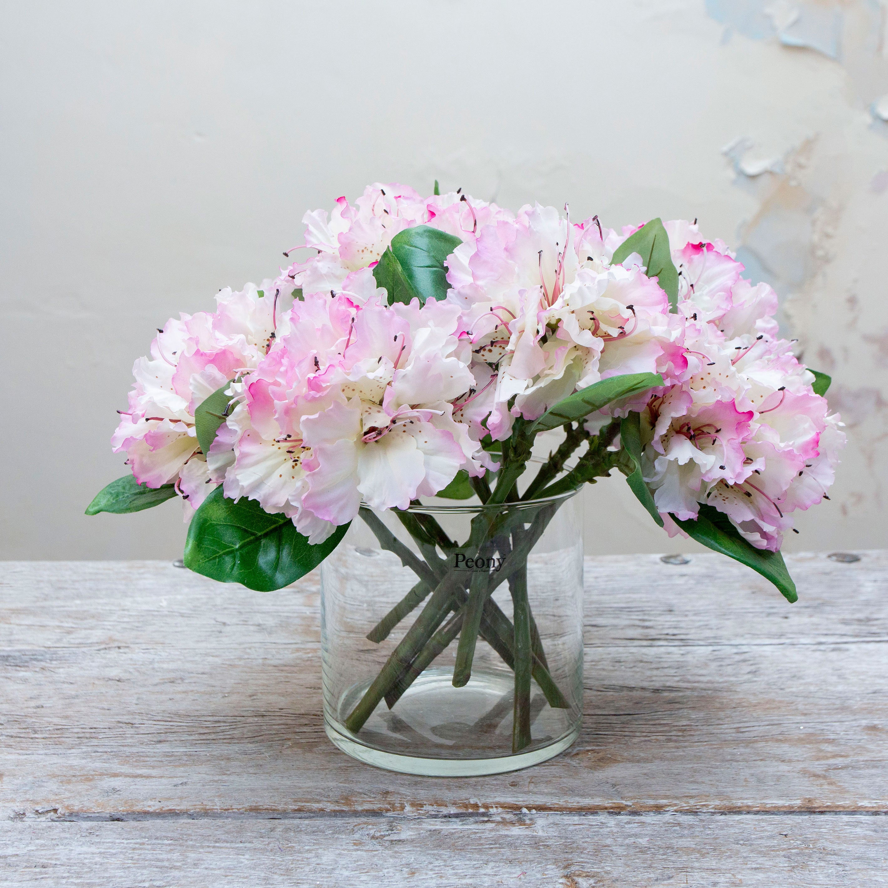 Artificial pink and white rhododendron stems displayed together in a vase for styling purposes