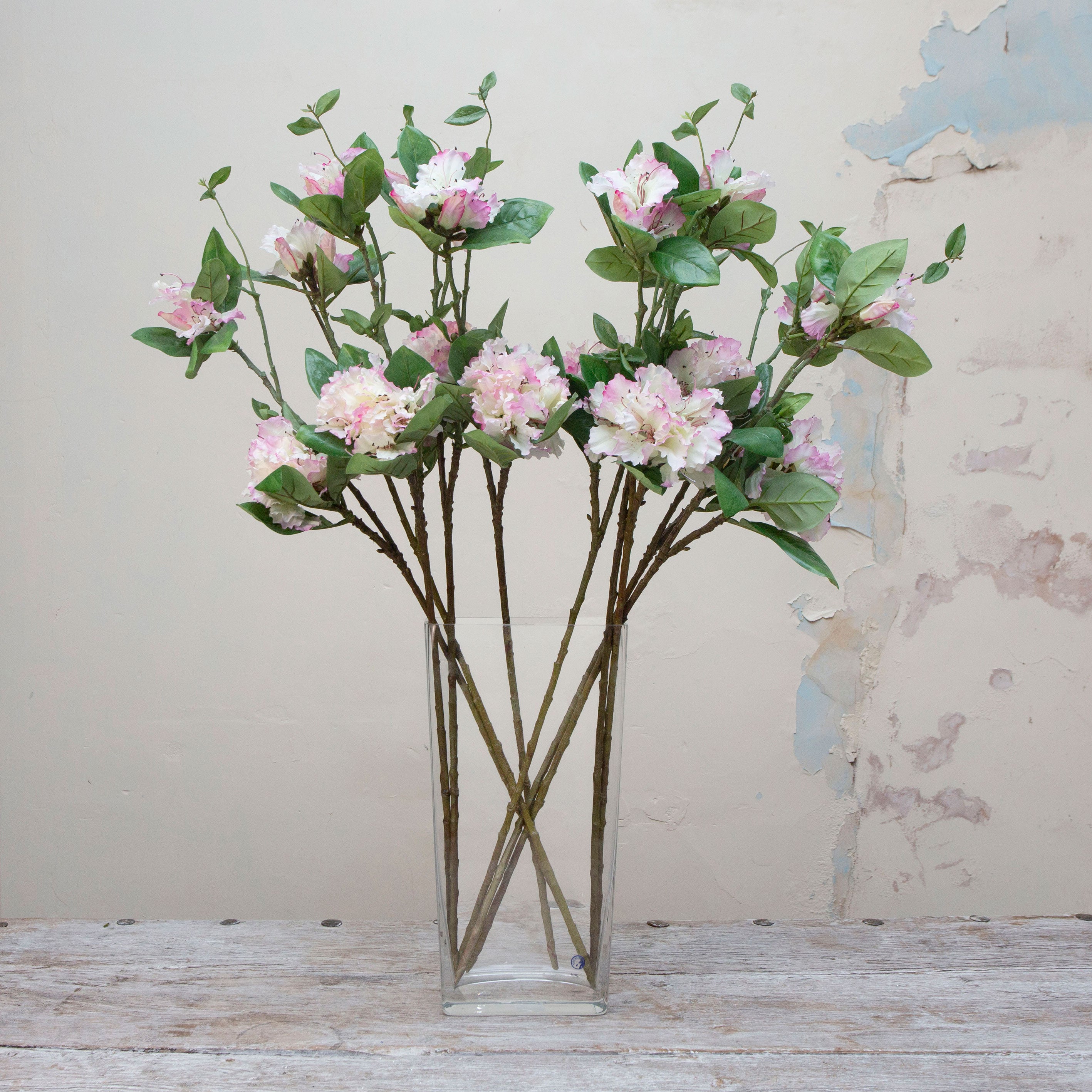 Artificial pink and white rhododendron stems displayed together in a vase for styling purposes.