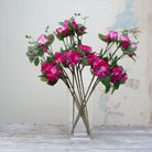 Artificial fuchsia pink rhododendron stems displayed together in a vase for styling purposes