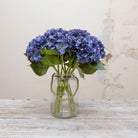 Artificial deep blue hydrangea stems displayed together in a vase for styling purposes.