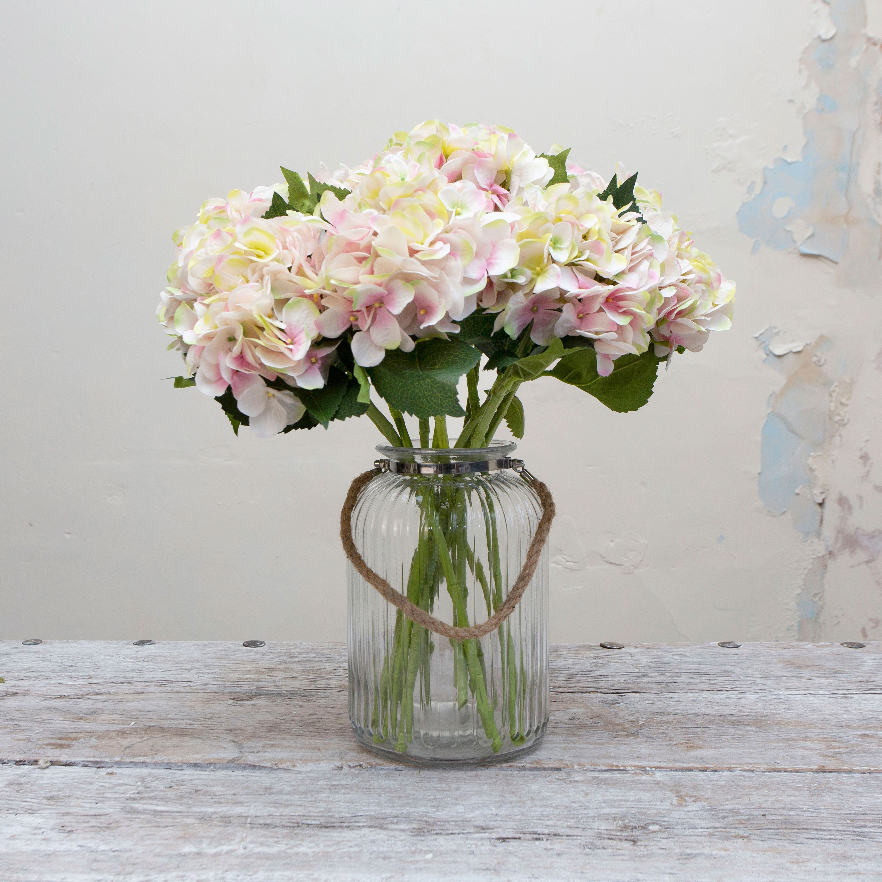 Artificial soft cream hydrangea stems with blush peach detailing displayed together in a vase for styling purpose