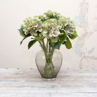 Artificial light green hydrangea stems with light purple detailing displayed together in a vase for styling purposes.