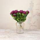 Artificial Chrysanthemum Stems with rich burgundy blooms and realistic green foliage displayed in a clear ribbed glass vase