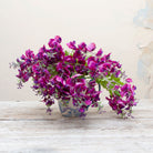 Artificial purple sweet pea stems displayed together in a vase for styling purposes.