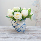 Artificial cream peony stems displayed together in a vase for styling purposes