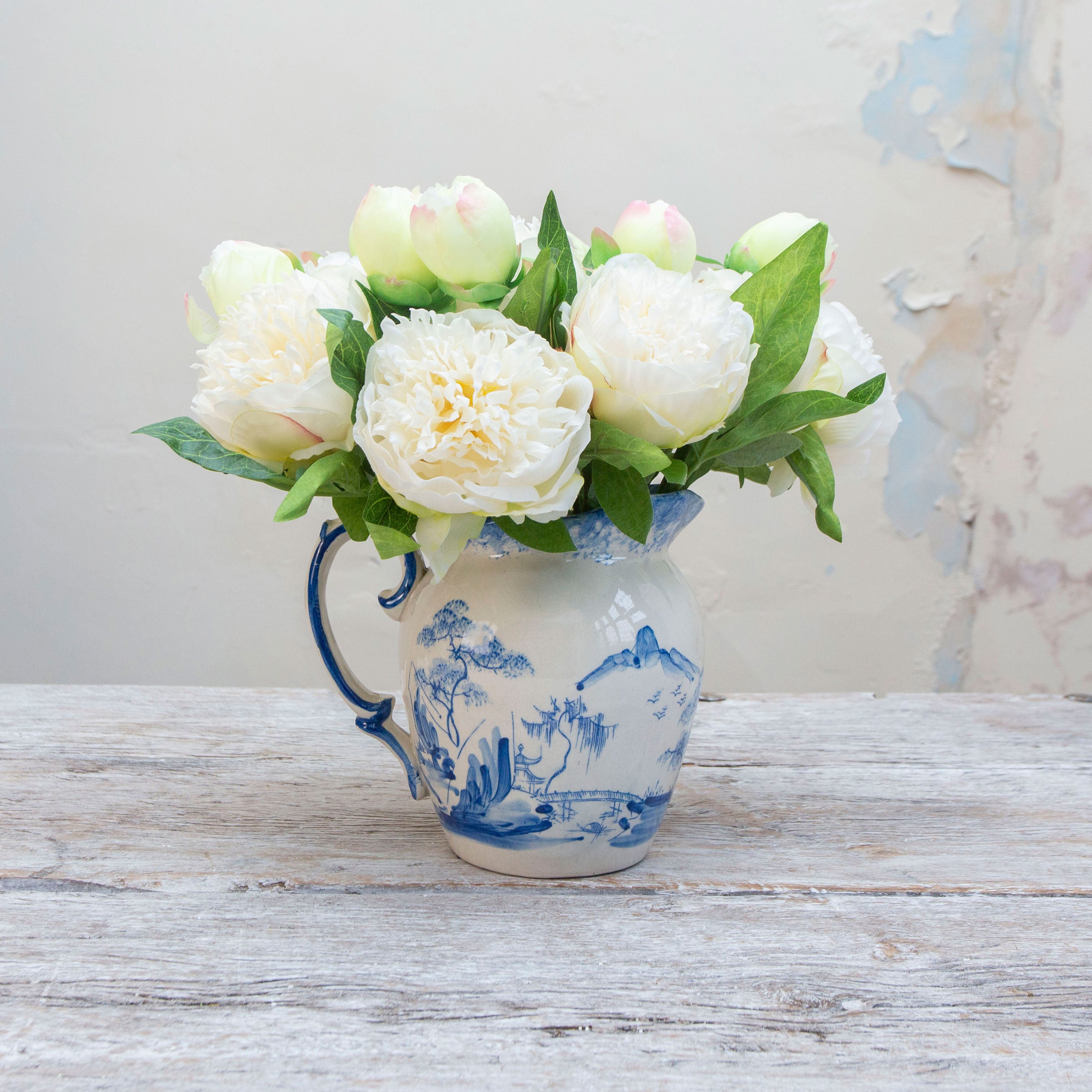 Artificial cream peony stems displayed together in a vase for styling purposes