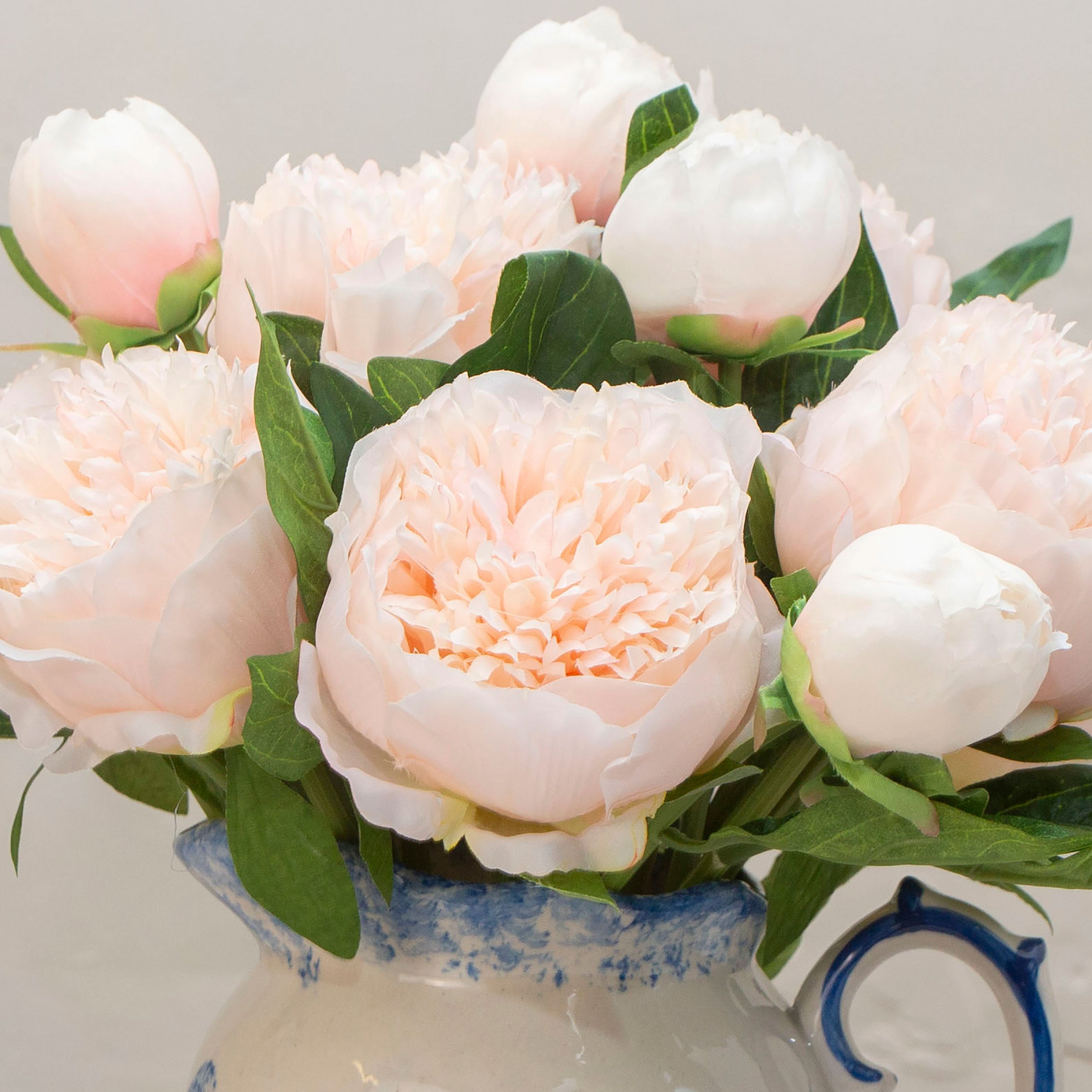 Close-up of artificial soft blush peach peony flowers showing layered petals and delicate colour variation