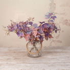 Artificial Leaf Foliage Stems with trailing purple, burgundy and muted autumn-toned leaves displayed in a clear ribbed glass vase