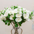 Close-up of artificial white rose spray flowers showing layered petals and soft white colour detail.
