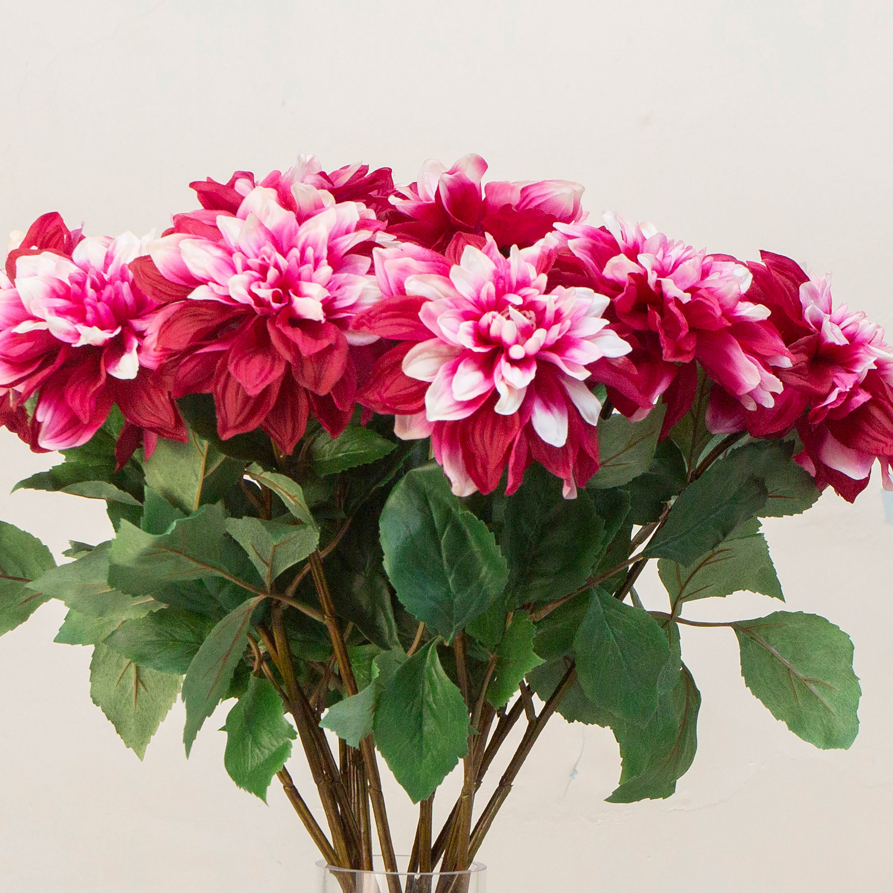 Close-up view of artificial magenta peonies with scattered white petals, showing detailed textures of the flowers.