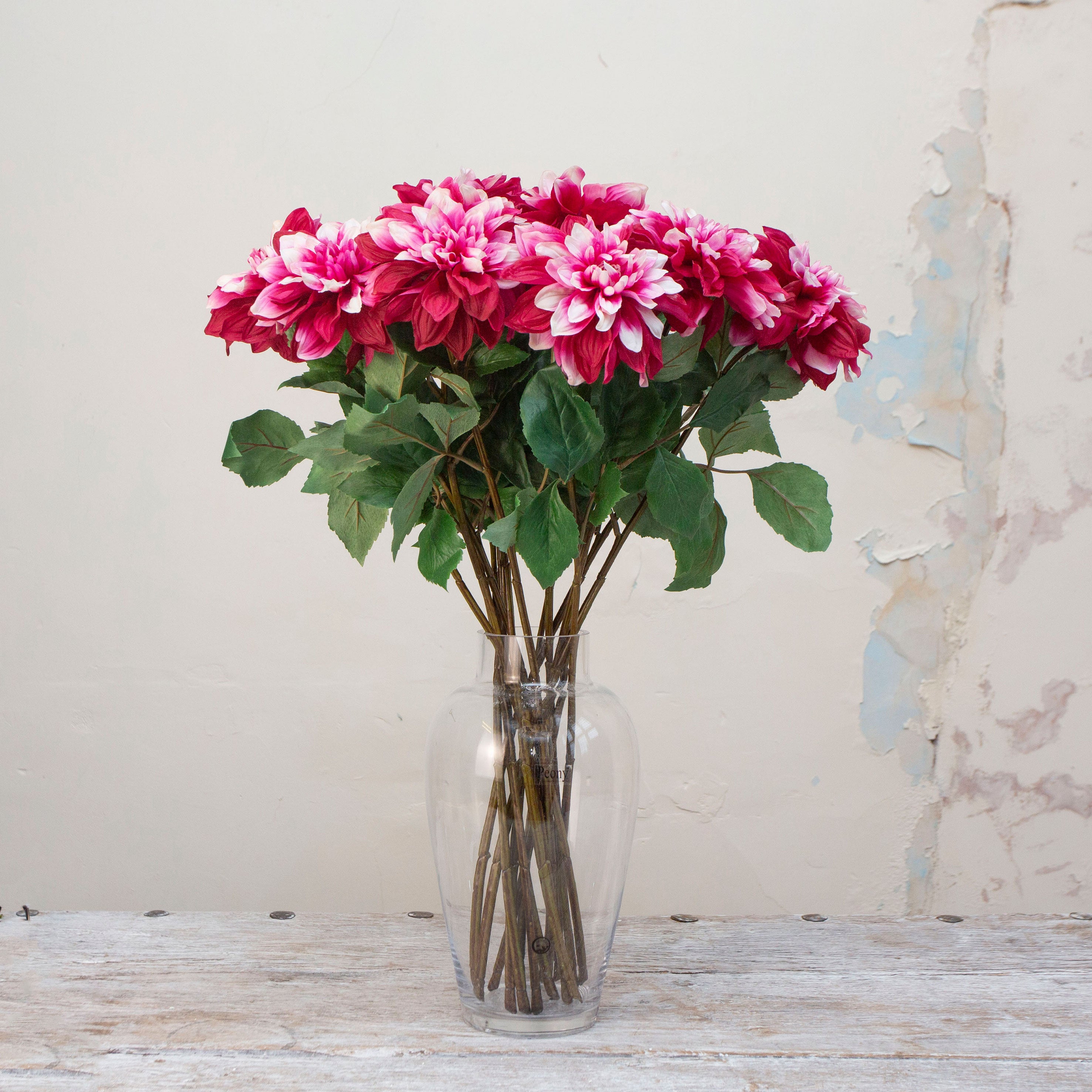 Artificial dahlia stems with magenta and white petals displayed in vase