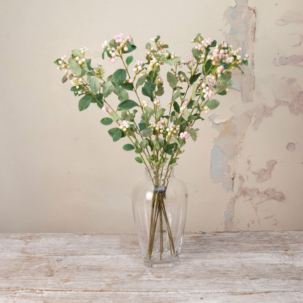 Artificial Snowberry Stems with soft pink and white berry clusters and realistic green foliage displayed in a clear glass vase