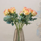 Close-up of artificial soft peach and yellow rose flowers showing layered petals and gentle colour variation