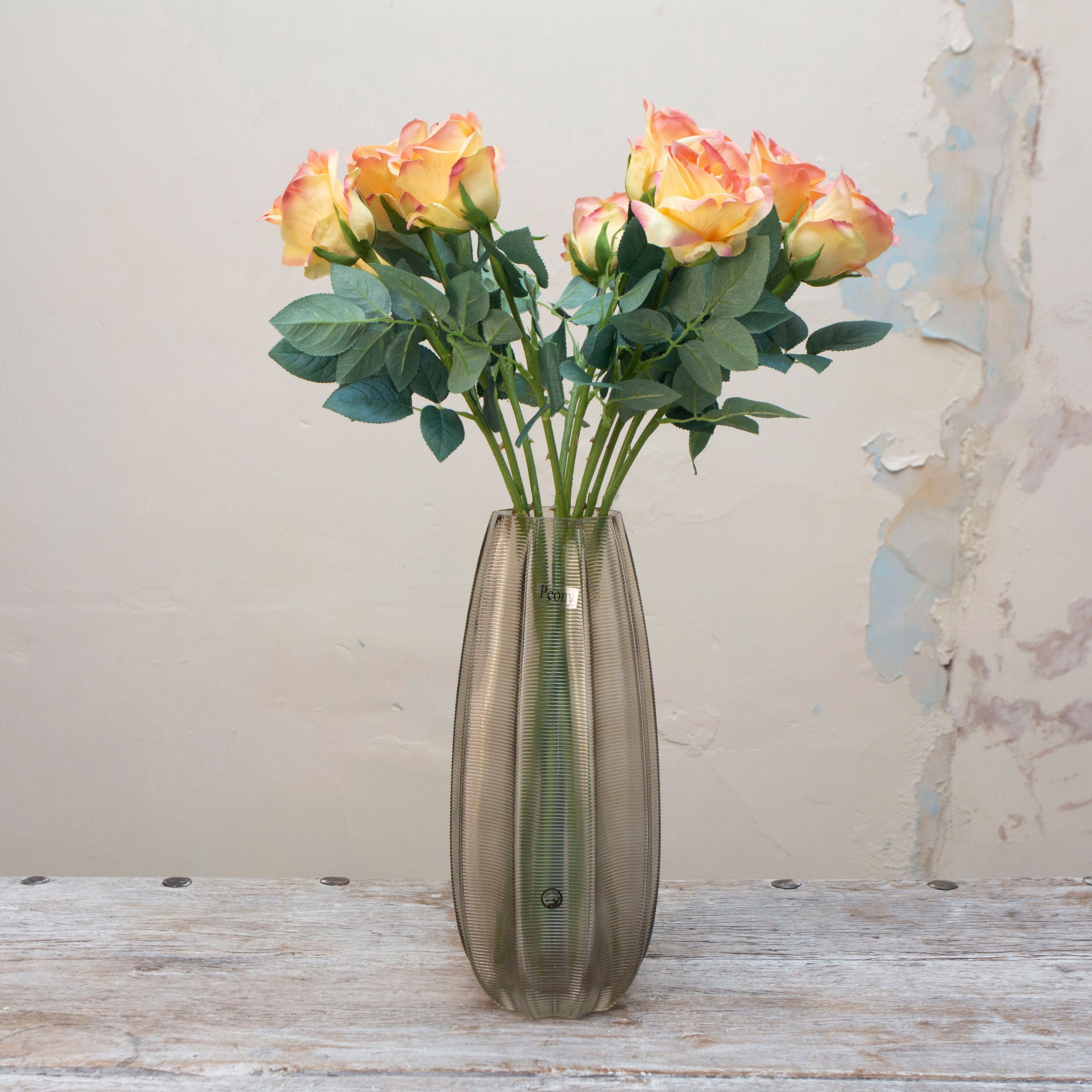 Artificial soft peach and yellow rose stems displayed together in a vase for styling purposes