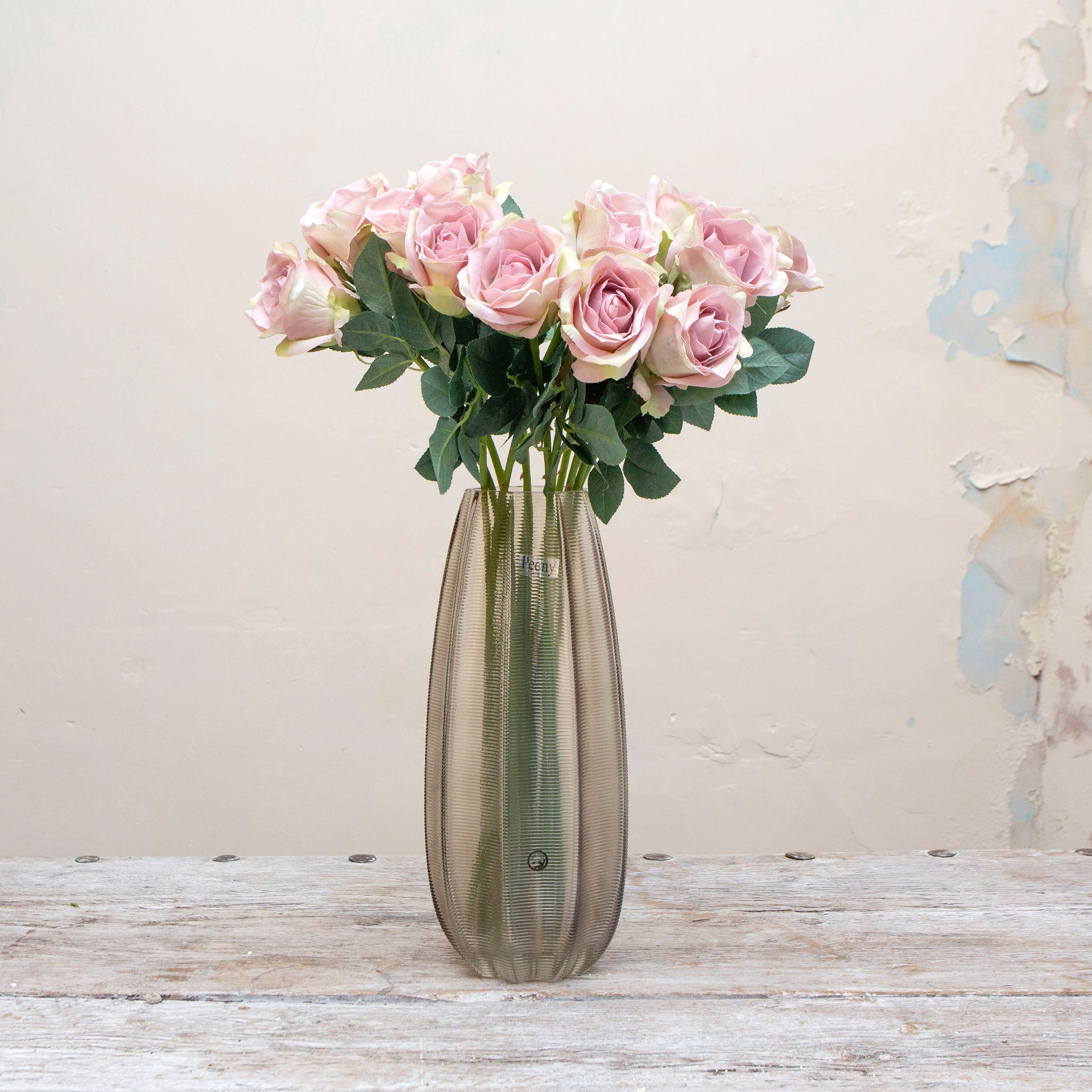 Artificial dusky pink rose stems displayed together in a vase for styling purposes.