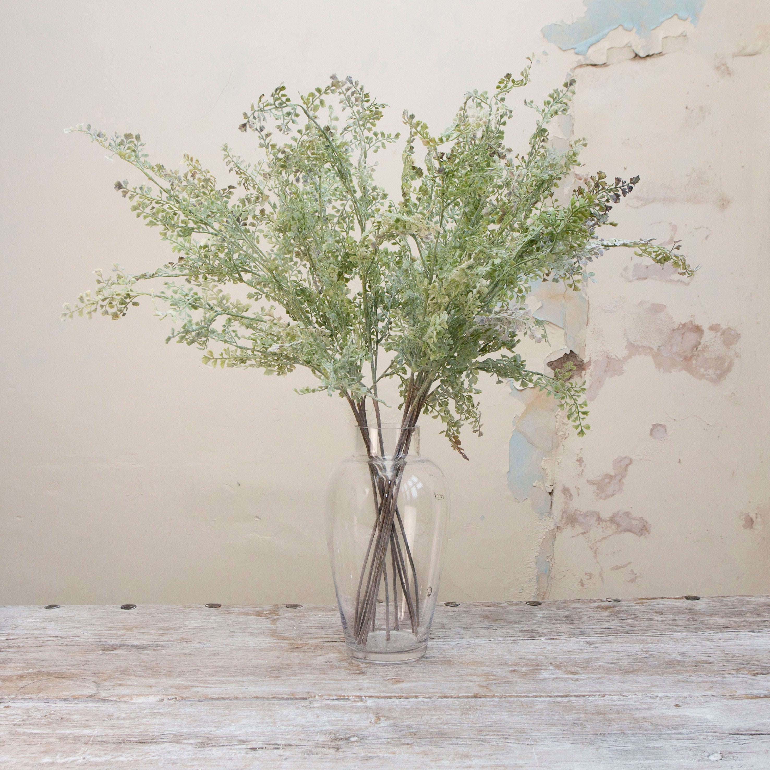 Artificial muted green shell fern greenery stems displayed in vase 