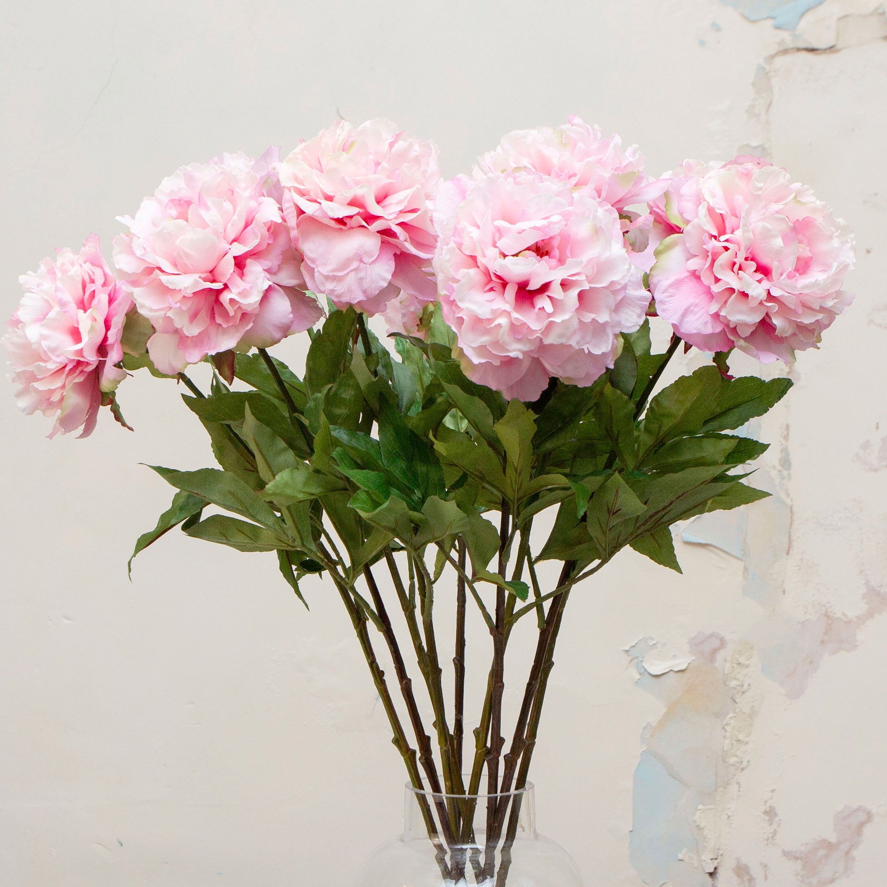 Close up of artificial pink peony stems with green leaves 