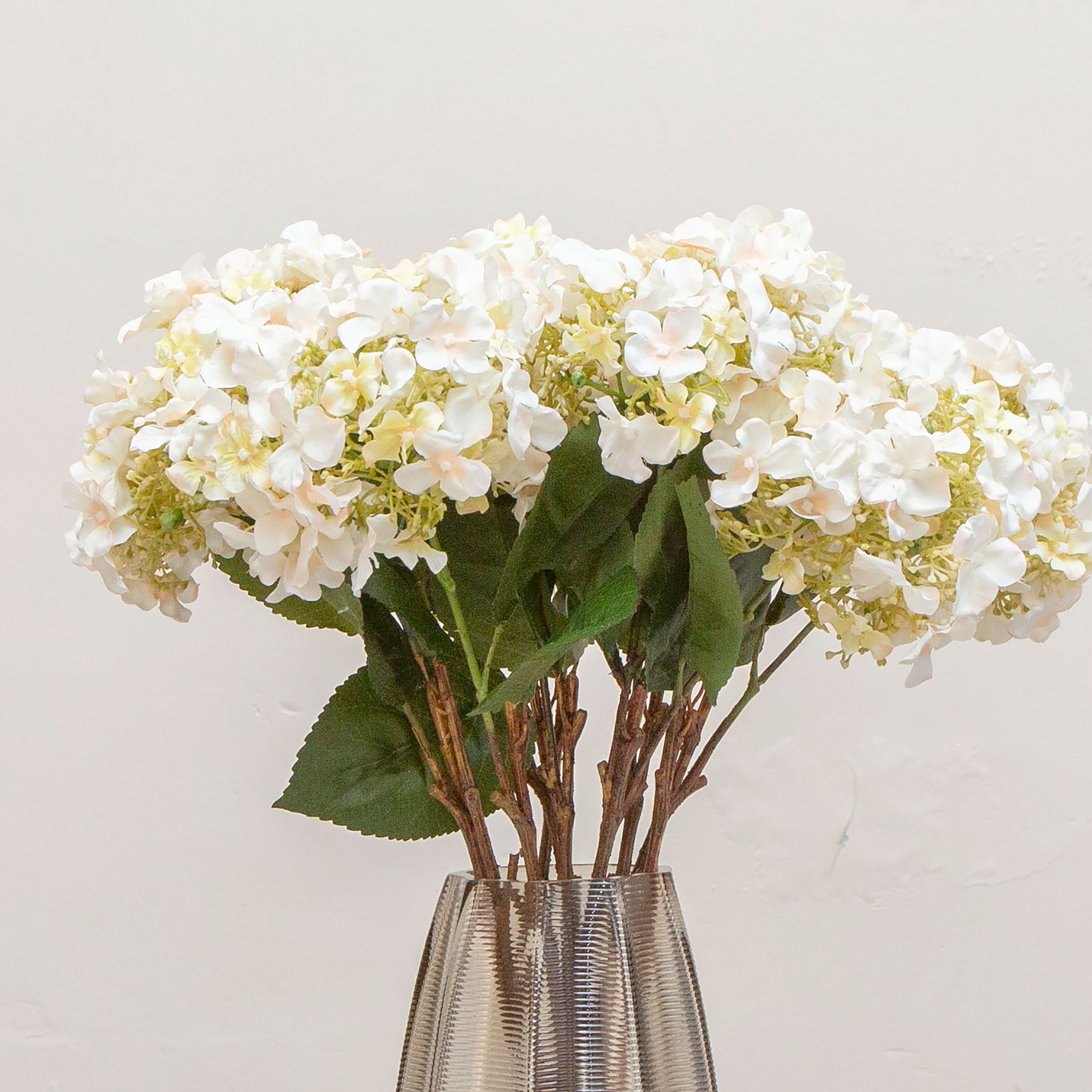 Close-up of artificial soft cream hydrangea flowers with peach detailing, showing clustered blooms and layered petals.