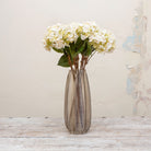 Artificial soft cream seedied hydrangea stems with peach detailing displayed together in a vase for styling purposes