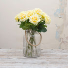 Artificial yellow rose stems displayed together in a vase for styling purposes