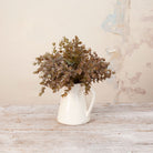 Artificial Mini Eucalyptus Bunch Stems with dense muted green and warm brown foliage displayed in a white ceramic jug